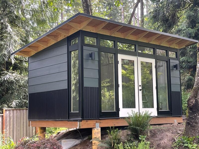 Completed modern black ADU on a wooded hillside lot