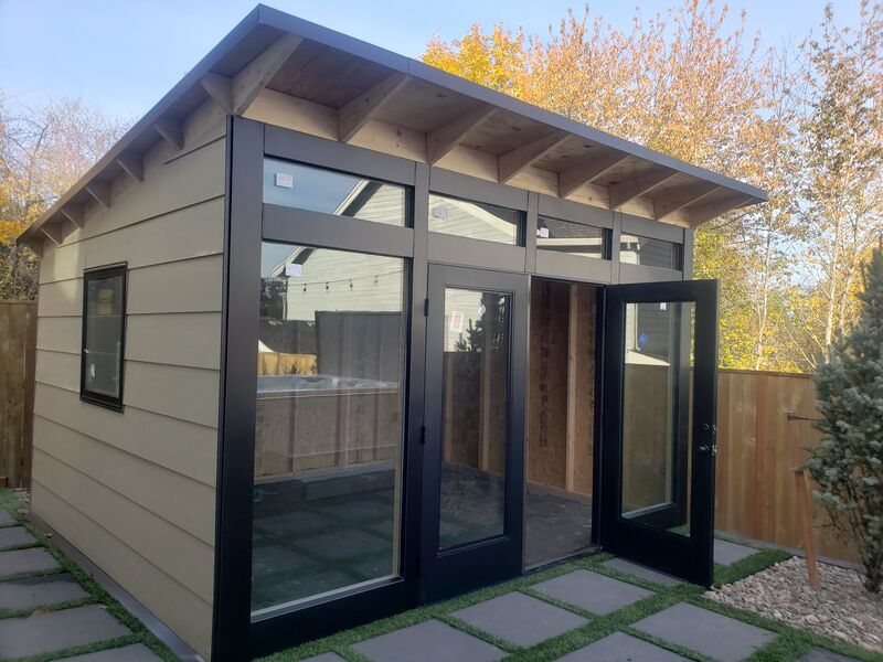 Completed backyard studio with black-framed glass doors and patio